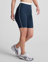 navy blue high-waisted biker shorts with a 5" inseam, waistband colorblock panels, and contrast piping detail on leg.